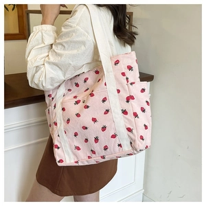 Dettaglio della borsa tote in velluto a coste rosa con stampe di fragole e tasche laterali