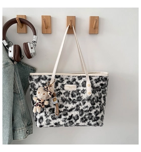 Detail of leopard print plush tote bag featuring a cute cat charm on wooden hook