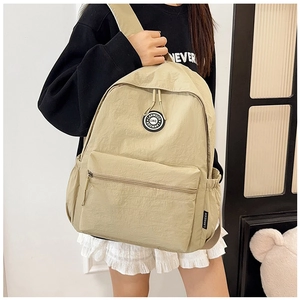 Close-up of khaki backpack showing the circular brand logo and durable nylon fabric texture