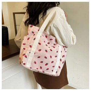 Dettaglio della borsa tote in velluto rosa con fragole e tasca laterale sulla spalla