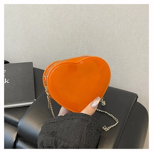 Detail einer leuchtend orangen Herz-Mini-Tasche mit Goldkette und glänzendem Finish