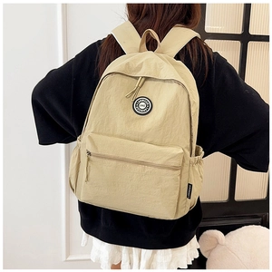 Detailed view of the beige nylon backpack with textured fabric and side pocket shown on model