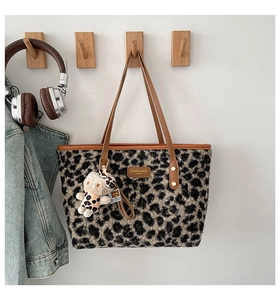 Detailed close-up of leopard print faux fur tote bag with leather strap and plush charm