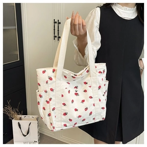 Dettaglio della borsa tote in velluto bianco con stampa a fragole e ampi manici in tela