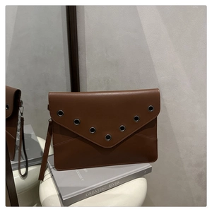 Détail de la pochette marron avec œillets métalliques en V et surpiqûres décoratives