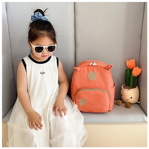 Detail of cute orange kids backpack with animal ears and star patch for daily travel