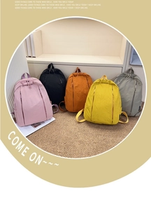 Detailed view of lightweight nylon backpacks in five pastel colors on a woven mat