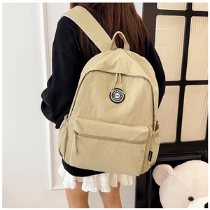 Detailed side view of khaki nylon backpack featuring smooth zippers and side water bottle pocket