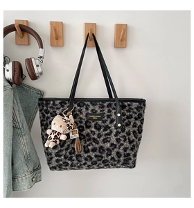 Detail of plush leopard print tote bag with leather straps and a cute kitten charm