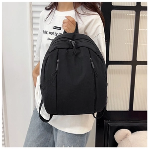 Detail of minimalist black backpack with dual zippers shown on model for daily commuting