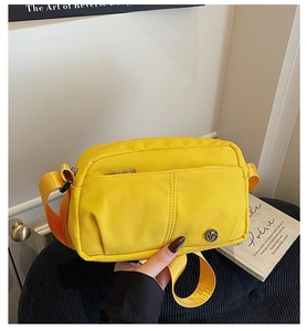Dettaglio borsa a tracolla in tela giallo brillante con logo in metallo e fascia