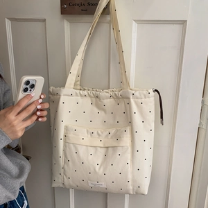 Minimalist beige drawstring tote bag with black polka dots and long shoulder straps