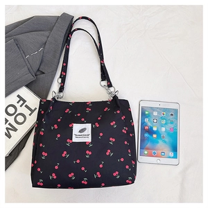 Flat lay of black cherry print canvas tote bag with magazine and tablet setup