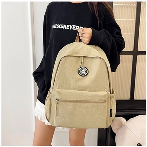 Detailed view of beige nylon backpack featuring side water bottle pocket and brand logo patch