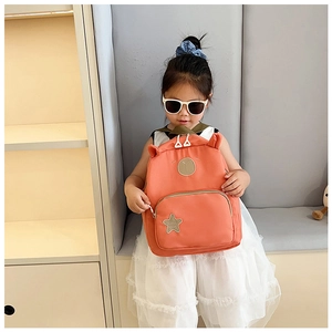 Detail shot of cute orange toddler backpack featuring cartoon ears and star badge