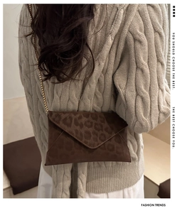 Detail view of leopard print envelope crossbody bag with gold chain strap on model