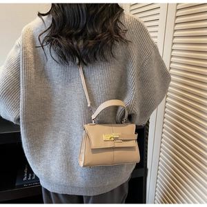 Beige leather square crossbody bag shown on a model with golden clasp detail