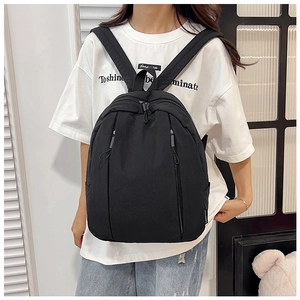 Detailed side view of black minimalist backpack showing side pocket and matte fabric texture