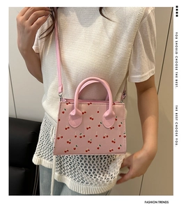 Pink sweet-style cherry print handbag worn by a model to show actual size and fit