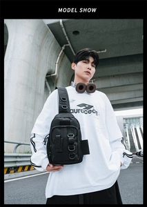 Street style shot of black tactical crossbody bag with multiple zipper pockets and loops
