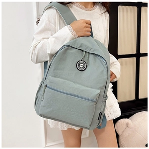 Close-up of light blue waterproof nylon backpack with minimalist front zipper pocket