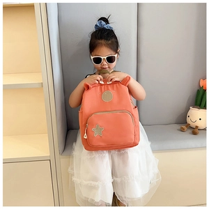 Detail view of coral orange cartoon backpack with star patch and 3D ears for kids