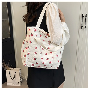 Dettaglio della trama della borsa tote in velluto a coste bianco con motivo a fragole rosse