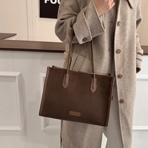 Close-up of dark brown vintage tote bag with metal Fashion logo and suede texture