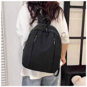 Close-up of lightweight black nylon backpack featuring vertical zip pockets and wide straps