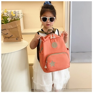 Little girl holding a cute orange backpack with cartoon bear embroidery and star details
