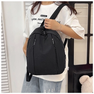 Side view of black nylon backpack with brand label worn by model for daily commute