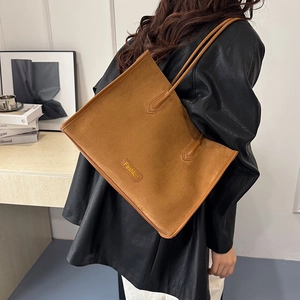Detail of tan suede tote bag with metal Fashion plate and slim leather shoulder strap