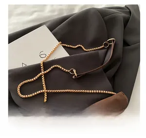 Detail of golden box chain strap with dark brown suede leather shoulder pad for women handbag