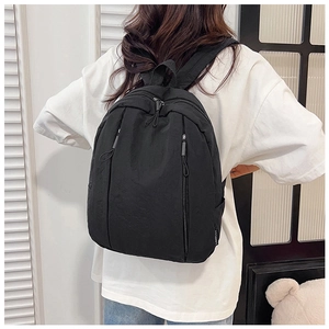 Detailed view of the black backpack's side profile with woven brand tag and zipper detail