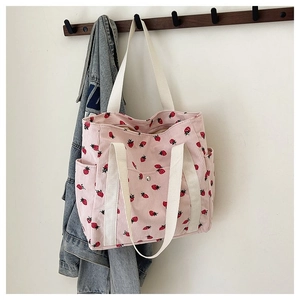 Dettaglio borsa tote in velluto rosa con fragole e manici in tessuto bianco