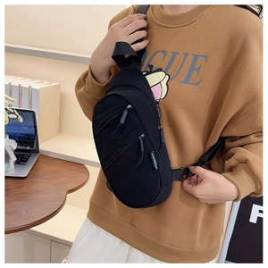 Détail du sac de poitrine en nylon noir montrant la texture étanche et les fermetures