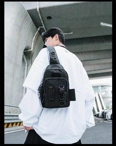 Detail of black tactical nylon chest bag with webbing system and zipper pocket on urban background