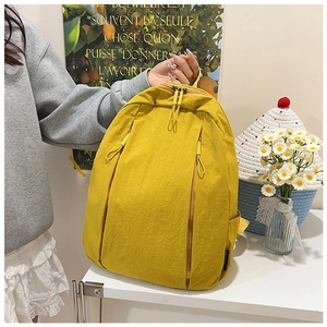 Detail of bright yellow wrinkled nylon backpack with vertical zippers and side pockets