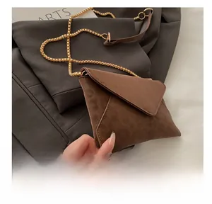 Detail of dark brown suede envelope bag with elegant golden bead chain and fine stitching