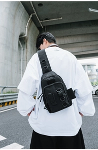 Close-up of black tactical nylon crossbody bag featuring D-hooks and functional webbing