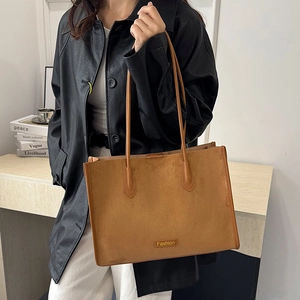 Close-up of brown textured leather tote bag featuring a Fashion plaque and long straps