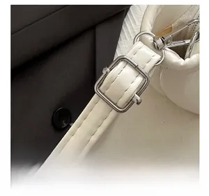 Detail of adjustable shoulder strap with silver metal buckle on white bucket bag