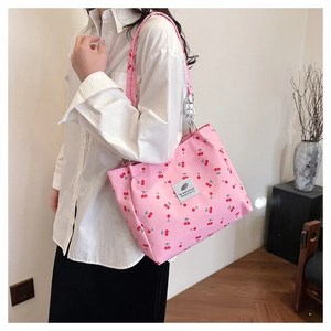 Detailed macro view of pink tote bag with cherry print and silver chain strap accent