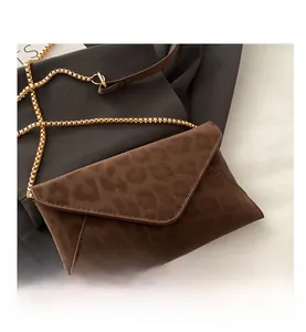 Detailed view of the dark brown leopard print texture and golden chain on envelope bag