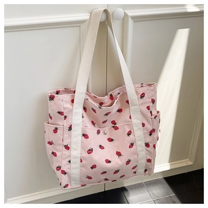Dettaglio della borsa tote in velluto a coste rosa con stampa fragola e cinghie bianche