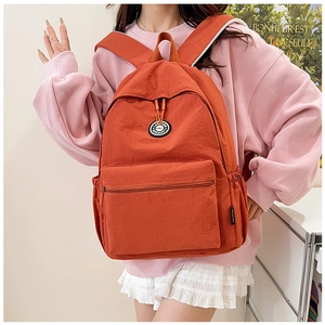 Detail of water-resistant nylon fabric and front pocket on the orange backpack