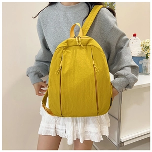 Detail showing the textured nylon fabric and vertical zipper pockets of this yellow backpack