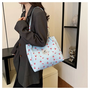 Lifestyle shot of a light blue canvas tote bag with cherry print and long shoulder straps
