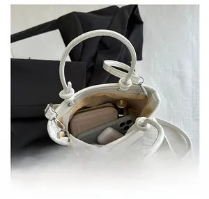 Top-down view of spacious interior of white bucket bag showing phone, wallet, and lipstick