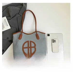 Detail of checkered tote bag with leather handles shown with tablet for size reference